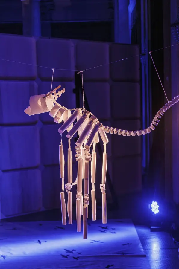 Scultura di carta del Segugio meccanico appesa a fili, in luce blu
