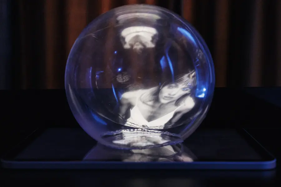 Sfera trasparente su uno schermo, con dentro il riflesso del volto di una donna